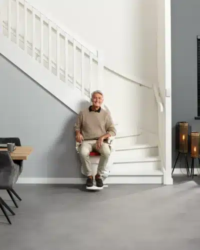 Homme dans son salon assis sur son monte escalier d'occasion