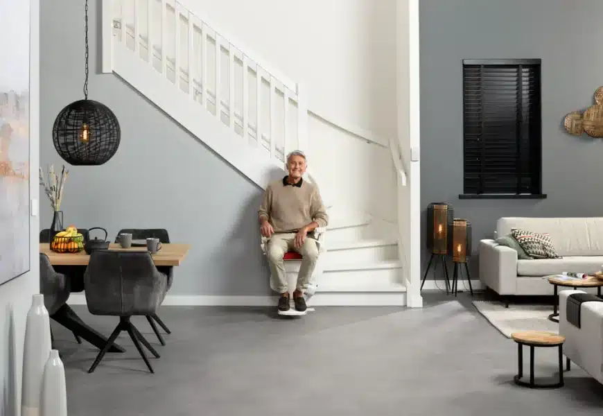 Homme dans son salon assis sur son monte escalier d'occasion